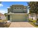 A beautiful home featuring green stucco, a two-car garage, and lush landscaping provides a welcoming curb appeal at 429 Rona Ln, Davenport, FL 33897