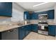 Well-lit kitchen featuring blue cabinets, stainless steel appliances, and granite countertops at 429 Rona Ln, Davenport, FL 33897