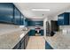 Spacious kitchen features blue cabinets, stainless appliances, and granite countertops at 429 Rona Ln, Davenport, FL 33897