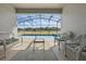 Enclosed patio with furniture overlooks a screened pool, yard, and pond at 634 Chadbury Way, Kissimmee, FL 34744