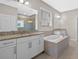 Bright bathroom featuring a double vanity with granite countertops and soaking tub at 690 Blue Citrus Ln, Minneola, FL 34715