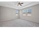 The primary bedroom features large windows, a ceiling fan, and plush carpeting at 690 Blue Citrus Ln, Minneola, FL 34715