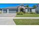 Inviting single-story home with manicured lawn and stone detailing, presenting a well-maintained and attractive exterior at 690 Blue Citrus Ln, Minneola, FL 34715