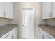 Laundry room features granite counters, white cabinets and convenient storage at 690 Blue Citrus Ln, Minneola, FL 34715
