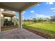 A covered patio with stone pavers overlooks a spacious, fenced backyard with ample green space at 8991 Fluffy Lie Ct, Davenport, FL 33896
