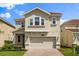 Charming two-story home with a well-manicured lawn and a brick paved driveway leading to the garage at 8991 Fluffy Lie Ct, Davenport, FL 33896
