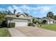 Stylish home featuring an attached two-car garage, manicured lawn, and lush landscaping at 907 Ridge Spring Ct, Apopka, FL 32712