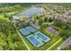 Aerial view of tennis courts near the lake, community pool, and parking in a leafy neighborhood at 9076 Lake Avon Dr, Orlando, FL 32829