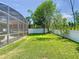 Spacious backyard featuring green grass, flowering plants and a screen enclosed patio at 9076 Lake Avon Dr, Orlando, FL 32829
