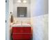 Modern half bath with a vessel sink atop red cabinetry and marble tile accent wall at 9076 Lake Avon Dr, Orlando, FL 32829