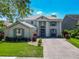 Charming two-story home featuring a well-manicured lawn, brick driveway, and a welcoming entrance at 9076 Lake Avon Dr, Orlando, FL 32829