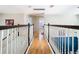 Wide hallway with wood floors and white railings, offering access to other rooms in the home at 9076 Lake Avon Dr, Orlando, FL 32829
