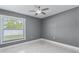 A gray painted bedroom has a ceiling fan, white tile flooring, and a large window for natural light at 116 Alcala Dr, Kissimmee, FL 34758