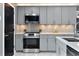 Well-equipped kitchen featuring gray cabinets, quartz countertops, tile backsplash, and stainless steel appliances at 116 Alcala Dr, Kissimmee, FL 34758