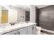 Modern bathroom featuring double sinks, marble countertop, tile accents, and a shower with a glass door at 1204 Blackheath Ct, Davenport, FL 33897