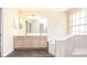 Bright bathroom featuring a dual-sink vanity, soaking tub, and a large window for ample natural light at 1204 Blackheath Ct, Davenport, FL 33897