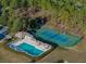 Aerial view of a community pool and tennis courts surrounded by mature trees at 1204 Blackheath Ct, Davenport, FL 33897