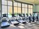 Well-equipped fitness center with treadmills, ellipticals, and large windows overlooking a lake view at 15707 Cutter Sail Pl, Winter Garden, FL 34787