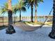 Tranquil hammock strung between palm trees on sandy beach, overlooking a serene lake and community homes in the background at 15707 Cutter Sail Pl, Winter Garden, FL 34787