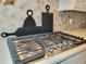 Stainless steel gas range cooktop set in white countertop with decorative cutting boards behind it at 15707 Cutter Sail Pl, Winter Garden, FL 34787
