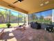 Beautiful screened lanai with outdoor seating, fan, and a view of the manicured lawn and mature landscaping at 15707 Cutter Sail Pl, Winter Garden, FL 34787