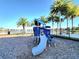The blue, modern playground by the lake with palm trees offers an inviting outdoor play area at 15707 Cutter Sail Pl, Winter Garden, FL 34787