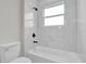 Modern bathroom featuring white tile, black fixtures, and a soaking tub with a window for natural light at 15823 Sw 27Th Avenue Rd, Ocala, FL 34473