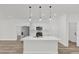Modern white kitchen features an island with pendant lighting, stainless steel appliances, and wood-look flooring at 15823 Sw 27Th Avenue Rd, Ocala, FL 34473