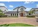 Stunning two-story home featuring a pristine white facade, manicured landscaping, and a circular brick driveway at 1661 Woodland Ave, Winter Park, FL 32789