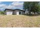 View of a large backyard with green grass, a sliding glass door, and a large mature tree at 1819 Carr St, Deland, FL 32720