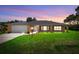 Charming brick home featuring well-maintained lawn, complementing the inviting facade at twilight at 1889 Eden Dr, Deltona, FL 32725