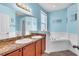 Bathroom featuring double sink vanity, soaking tub, and stylish nautical themed decor at 344 Highland Meadows St, Davenport, FL 33837