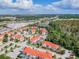 Aerial view featuring rows of townhomes with red tile roofs, community landscaping, and surrounding trees and commercial areas at 4504 Alberto Cir, Kissimmee, FL 34746