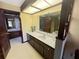 A spacious bathroom with a dual-sink vanity, neutral countertops and dark wood cabinets at 6084 Masters Blvd, Orlando, FL 32819
