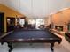 An expansive living room with a pool table, brick fireplace, and comfortable leather seating for entertaining at 6084 Masters Blvd, Orlando, FL 32819