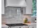 Close up of a modern kitchen's gas stovetop, white cabinets, and marble backsplash at 804 E 24Th Ave, New Smyrna Beach, FL 32169