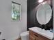 Contemporary powder room with sleek fixtures, wood vanity, round mirror and stylish accent wall at 804 E 24Th Ave, New Smyrna Beach, FL 32169