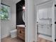 Chic powder room with wood vanity, accent wall, and views into bright laundry room at 804 E 24Th Ave, New Smyrna Beach, FL 32169