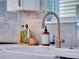 A farmhouse sink with a modern faucet, soap, and marble backsplash provide a clean and stylish kitchen at 804 E 24Th Ave, New Smyrna Beach, FL 32169