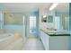 Bright bathroom featuring double vanities, glass-enclosed shower, and natural light through glass block windows at 847 Coventry Rd, Davenport, FL 33897