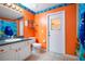 Bright bathroom with an orange wall, a single sink vanity, and a fish-themed shower curtain at 847 Coventry Rd, Davenport, FL 33897