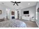 Cozy bedroom with a ceiling fan includes a TV, seating, and views to the ensuite bathroom at 16238 Misty Hills Ave, Winter Garden, FL 34787