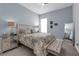 Stylishly decorated bedroom with light blue walls, tufted bench, and mirrored nightstand at 16238 Misty Hills Ave, Winter Garden, FL 34787