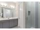 Modern bathroom with double vanity, gray cabinets, and glass-enclosed shower at 1014 Jack Nicklaus Ct, Reunion, FL 34747