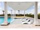 Poolside lounging area with modern pergola and relaxing waterfall feature at 1014 Jack Nicklaus Ct, Reunion, FL 34747