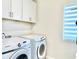 Functional laundry room with front-loading Samsung washer and dryer, storage cabinets, and a modern window shade at 10275 Park Estates Ave, Orlando, FL 32836