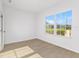 This bedroom features wood-look floors and a large window with a view of lush green grass and other houses at 104 Alta Vista Way, Davenport, FL 33837