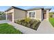 Close-up of a home's exterior with tidy landscaping and a walkway to the front door at 104 Alta Vista Way, Davenport, FL 33837