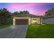 Twilight image of a cozy home with a tidy lawn, long driveway, and attached garage at 104 Alta Vista Way, Davenport, FL 33837