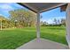Expansive backyard featuring a green lawn, mature trees in the distance, and a covered patio at 108 Alta Vista Way, Davenport, FL 33837